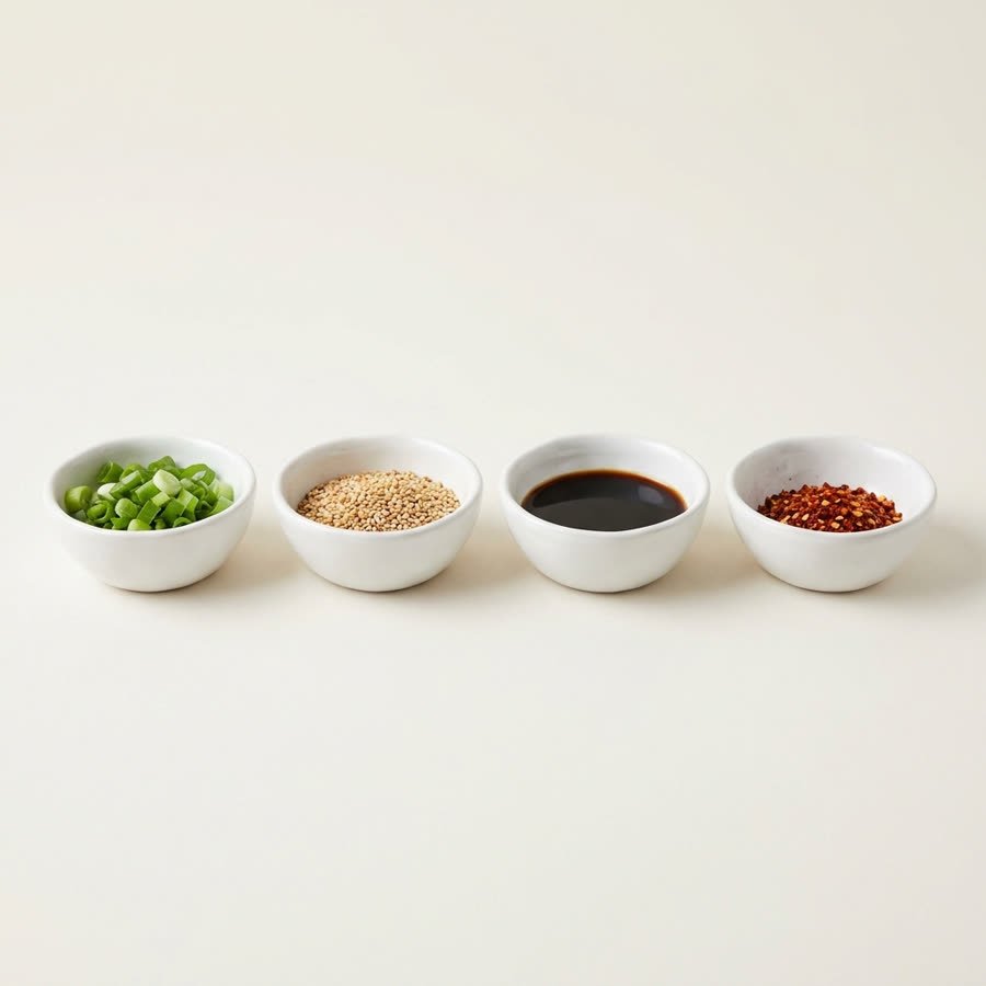 Four white prep bowls in a row holding spring onion, sesame, soy and chilli