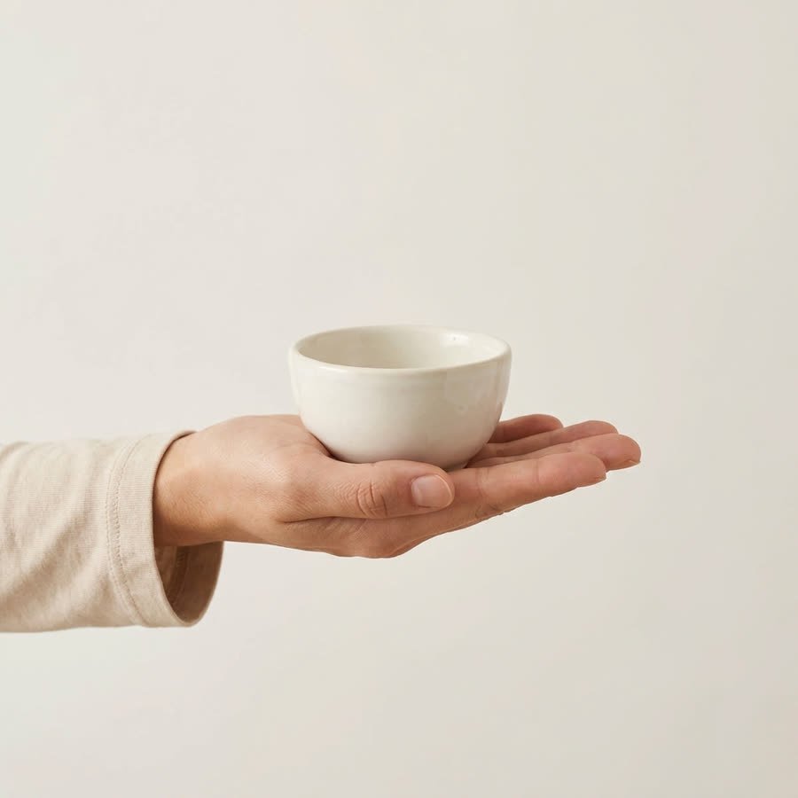 A white prep bowl held in an open hand, showing how small it is